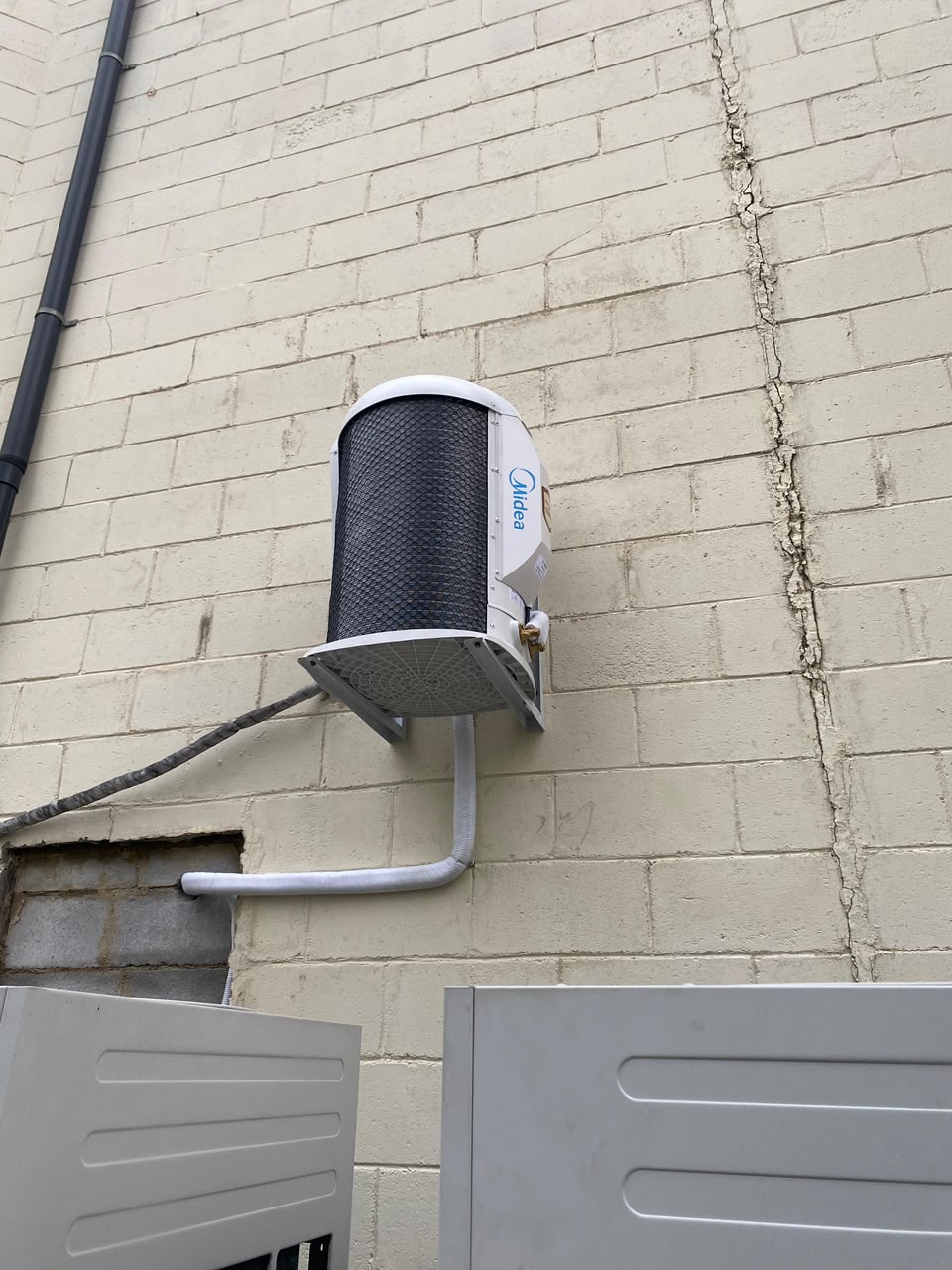 Condensadora Midea instalada em parede externa de tijolos